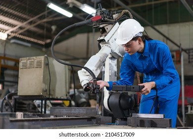 Female automation engineer wear a blue uniform with helmet safety inspection control a robot arm welding machine with a remote system in an industrial factory. Artificial intelligence concept. - Powered by Shutterstock