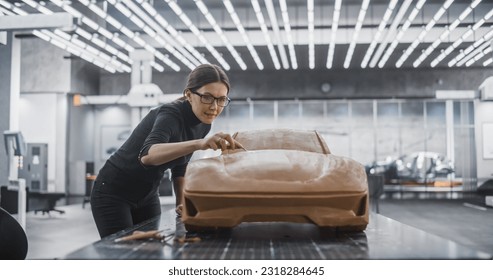 Female Automotive Designer Using a Spatula to Create a Prototype Car Out of Polymer Modeling Clay. Focused Modeler Working in Research and Development Studio at a Vehicle Production Factory - Powered by Shutterstock