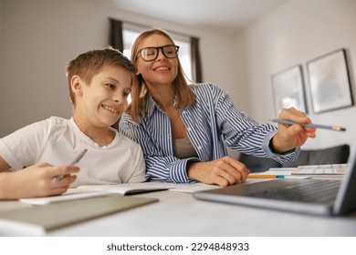 Female babysitter is teaching little boy use laptop application during studying - Powered by Shutterstock