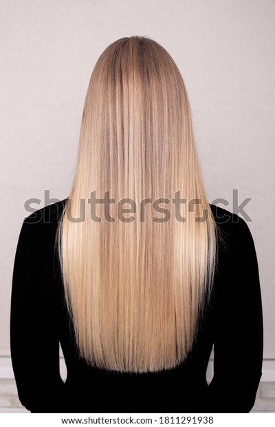 \
Female back with long blonde healthy hair in\
hairdressing salon