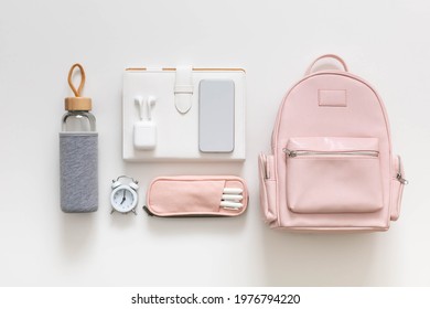 Female backpack with smartphone, stationery, clothes and shoes isolated on white. Top view stylish personal accessories and clothing. Student bag storage organization. Concept of back to school
