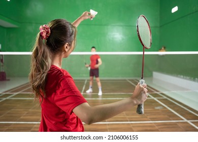 Female badminton player holding shuttlecock and racket in service position