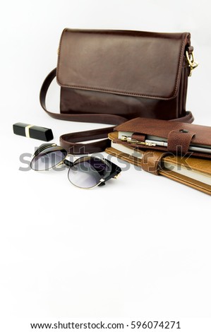 Female bag, glasses, lipstick, notepad and pen not against white background