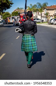 Female Bagpipe Player In A Kilt Walking Behind A Fire Truck 