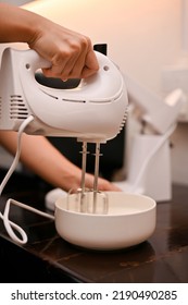 A Female Baker Beat The Eggs, Sugar, And Flour In A Mixing Bowl With A Handheld Beater. cupcake Recipe Concept, Close-up Image