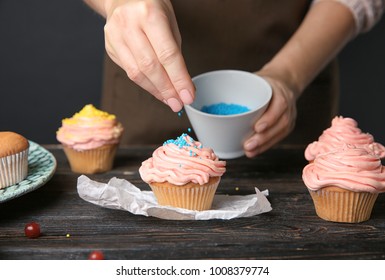 Female Baker Decorating Tasty Cupcake With Sprinkles At Table