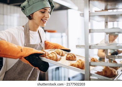 Female baker at the kitchen holding freshly baked croiisants - Powered by Shutterstock