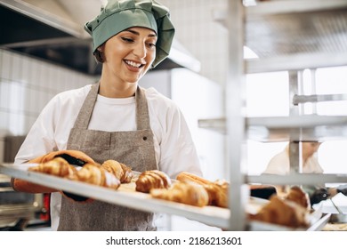 Female baker at the kitchen holding freshly baked croiisants - Powered by Shutterstock