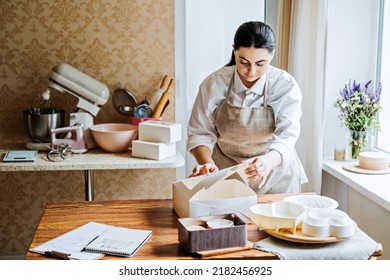 Female Baker, Pastry Chef Preparing Cake Order. Arabic Asian Woman Making Cake For Online Delivery