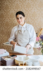 Female Baker, Pastry Chef Preparing Cake Order. Arabic Asian Woman Making Cake For Online Delivery