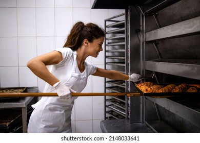 Female Baker In White Uniform Working In Bakery Production Baking Pastry In The Oven.