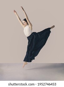 female ballet dancer in  long black skirt and white leotard jumping, art concept