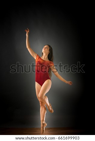 Female ballet dancer on one leg with arms stretched out, studio shot. caucasian fit pretty skinny athletic