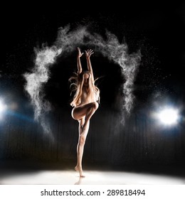 female ballet dancer posing on stage in theater with powder