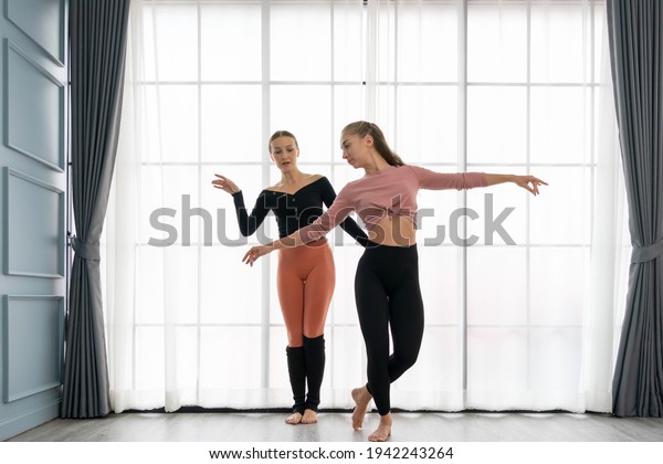 Female ballet teachers training ballerina to\
have right postures in the private class at home studio.\
Choreographer teaching caucasian dancers to movements of modern\
music. Concept of dance\
rehearsal