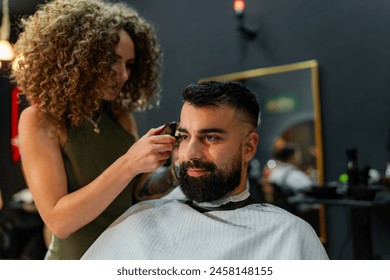 Female barber meticulously trims and styles a male client's hair with electric clippers in a modern barber shop, ensuring a precise and stylish cut. - Powered by Shutterstock