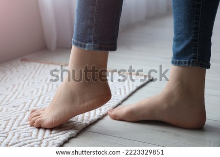 Female bare feet on rug, closeup