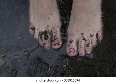 Female Bare Feet With Red Manicure Immersed In Water And Dirt, Overhead Shot