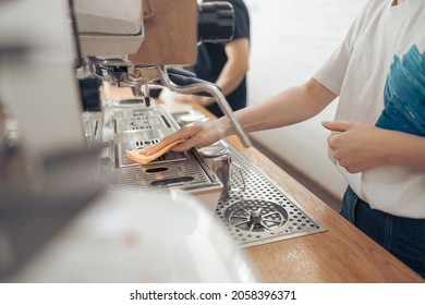 Female barista cleaning coffee machine in cafeteria - Powered by Shutterstock