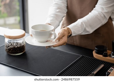 Female barista holding a coffee cup on the counter working in a coffee shop. Service, small business. - Powered by Shutterstock