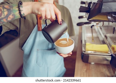 Female Barista Making Latte Art In Coffee Shop