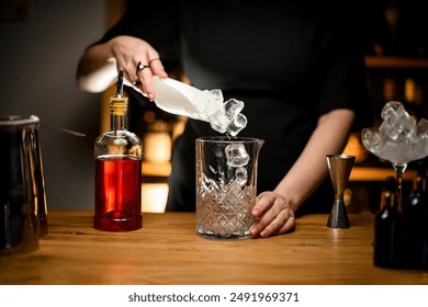 Female bartender hands scooping ice cubes into a glass for mixing cocktails - Powered by Shutterstock