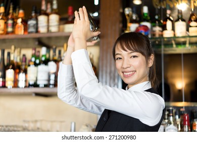 Female Bartender Making Cocktail With Shaker At Bar