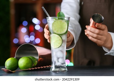 Female Bartender Making Fresh Mojito On Table In Bar