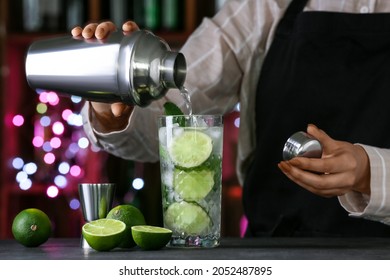 Female Bartender Making Fresh Mojito On Table In Bar