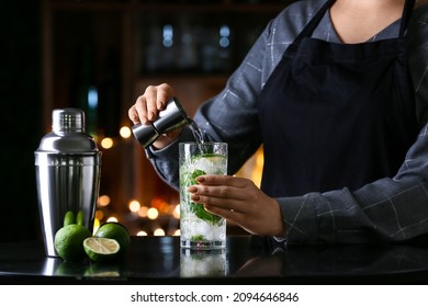Female Bartender Making Tasty Mojito On Table In Bar