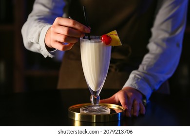 Female Bartender Making Tasty Pina Colada Cocktail On Table In Bar