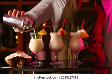 Female Bartender Making Tasty Pina Colada Cocktail On Table In Bar