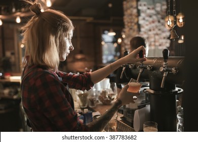 Female Bartender Pouring Beer From Tap At Bar