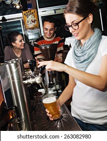 Female Bartender Pours The Beer Into A Glass