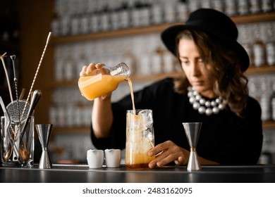 Female bartender pours juice from a jar into a tall glass - Powered by Shutterstock