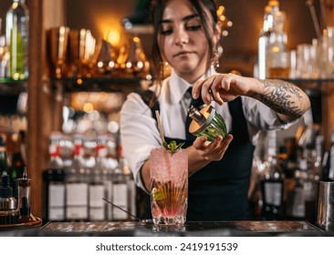 Female bartender preparing a mojito cocktail served in a tall glass in a traditional cocktail bar - Powered by Shutterstock