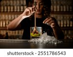 Female bartender pulls a muddler Turbo Swizzle Barta from a glass with water and lemon