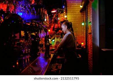 Female Bartender Standing Behind The Counter Preparing An Order For A Customer While Working In A Bar Or Pub.