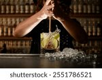 Female bartender vigorously squeezes lemons in a glass with a drink using the Turbo Swizzle Barta muddler