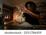 Female bartender vigorously swirls a Turbo Swizzle Barta muddler in a lemon cocktail, the liquid flying out of the glass