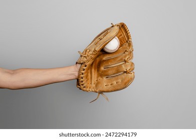 Female baseball gloved hand catches ball. Gray background. Active sport, championship, victory - Powered by Shutterstock