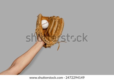 Female baseball gloved hand catches ball. Gray background. Active sport, championship, victory
