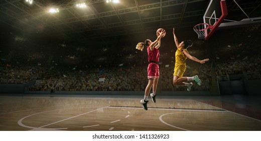 Female basketball players fight for the ball. Basketball player makes slam dunk on big professional arena during the game