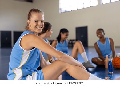 Female basketball players sitting on court, smiling and relaxing after practice. team, sports, women, friendship, teamwork, exercise - Powered by Shutterstock