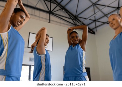 Female basketball team stretching together in gym, preparing for practice. Teamwork, sports, fitness, training, exercise, athletes - Powered by Shutterstock