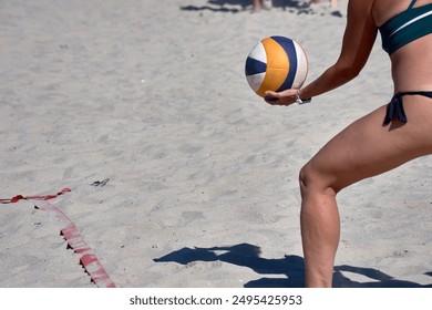 A female beach volleyball player is captured in the critical moment of serving during a 3x3 match. Her intense focus and perfect form highlight the skill and athleticism required in beach volleyball. - Powered by Shutterstock