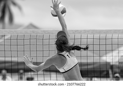 A Female Beach Volleyball Player Is Rising At The Net To Strike The Ball The Ball In Black And White Image Format