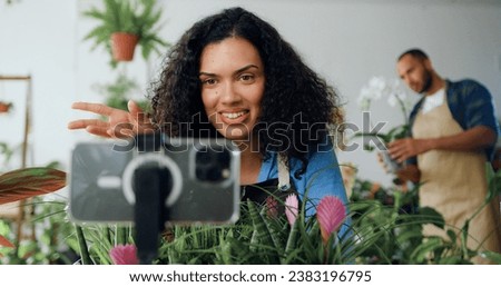 Female beautiful gardener making live conference for followers Owner flowers shop woman smile and Live Streaming on mobile application by mobile phone for sell flower.