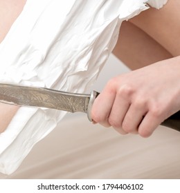 Female beautiful legs of young woman with foam during shaving by knife on white background