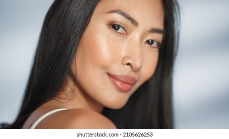 Female Beauty Portrait. Beautiful Asian Brunette Woman Posing, Smiling, Touching Her Face With Natural, Healthy Skin. Wellness And Skincare Concept On Soft Isolated Background. Close Up.